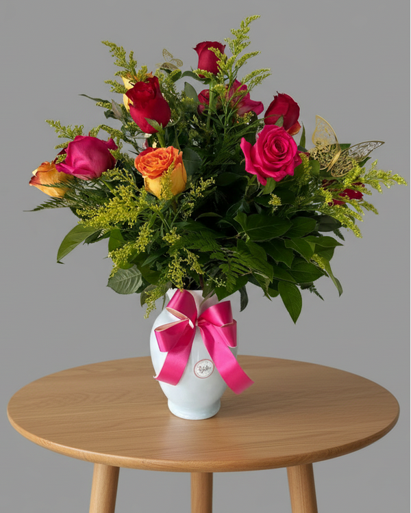 Classic bouquet of 12 roses in assorted colors with greenery in a glass vase