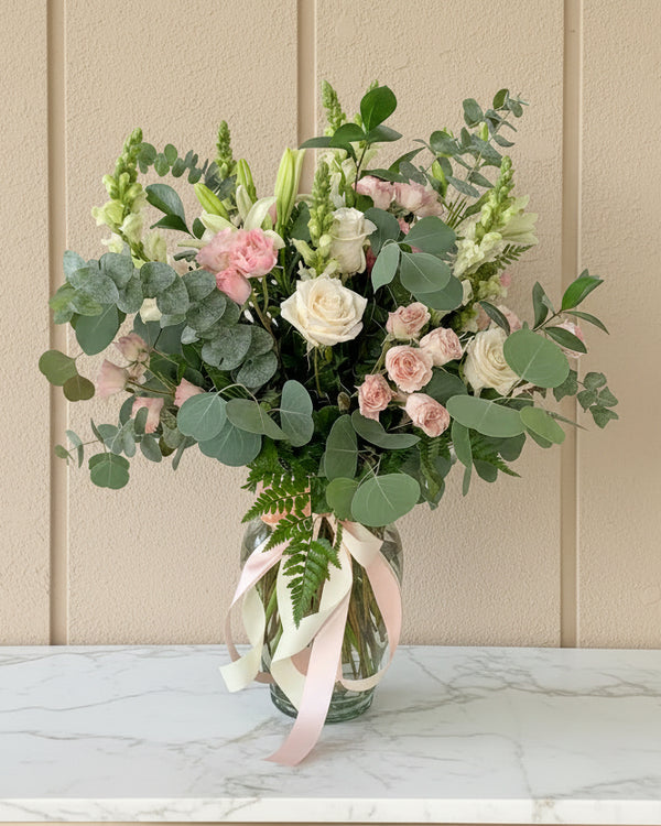Arrangement of roses and mini-roses, lilies, and stock flowers, accompanied by assorted eucalyptus. Perfect for any occasion and Valentine's Day.